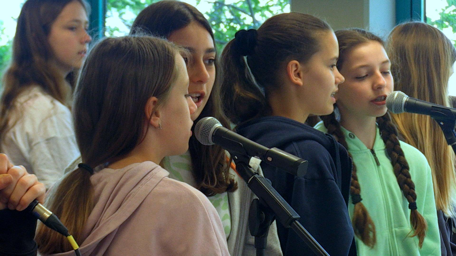 Schülerinnen singen in Mikrofone.