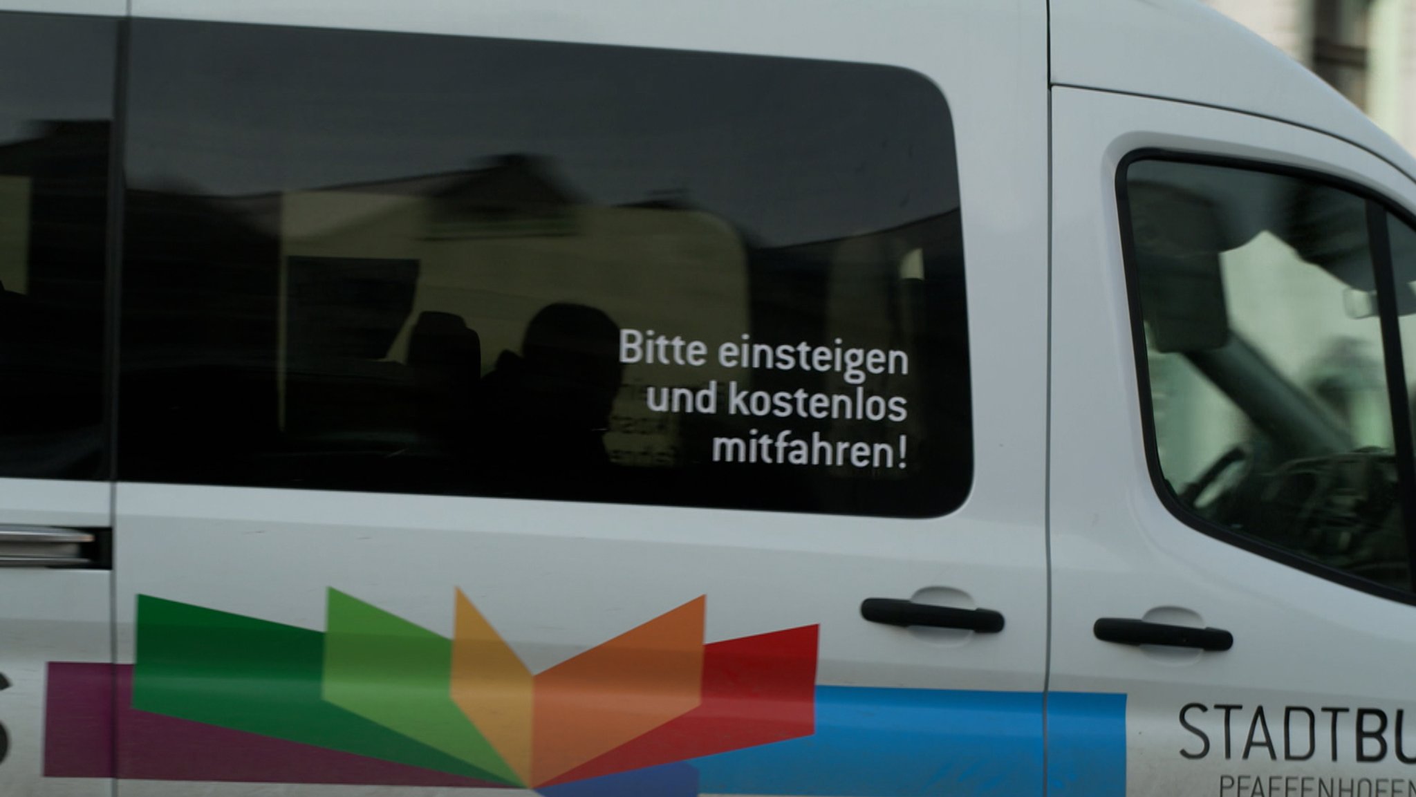 Zu sehen ist ein Auto mit dem Aufdruck auf der Scheibe "Bitte einsteigen und kostenlos mitfahren!"