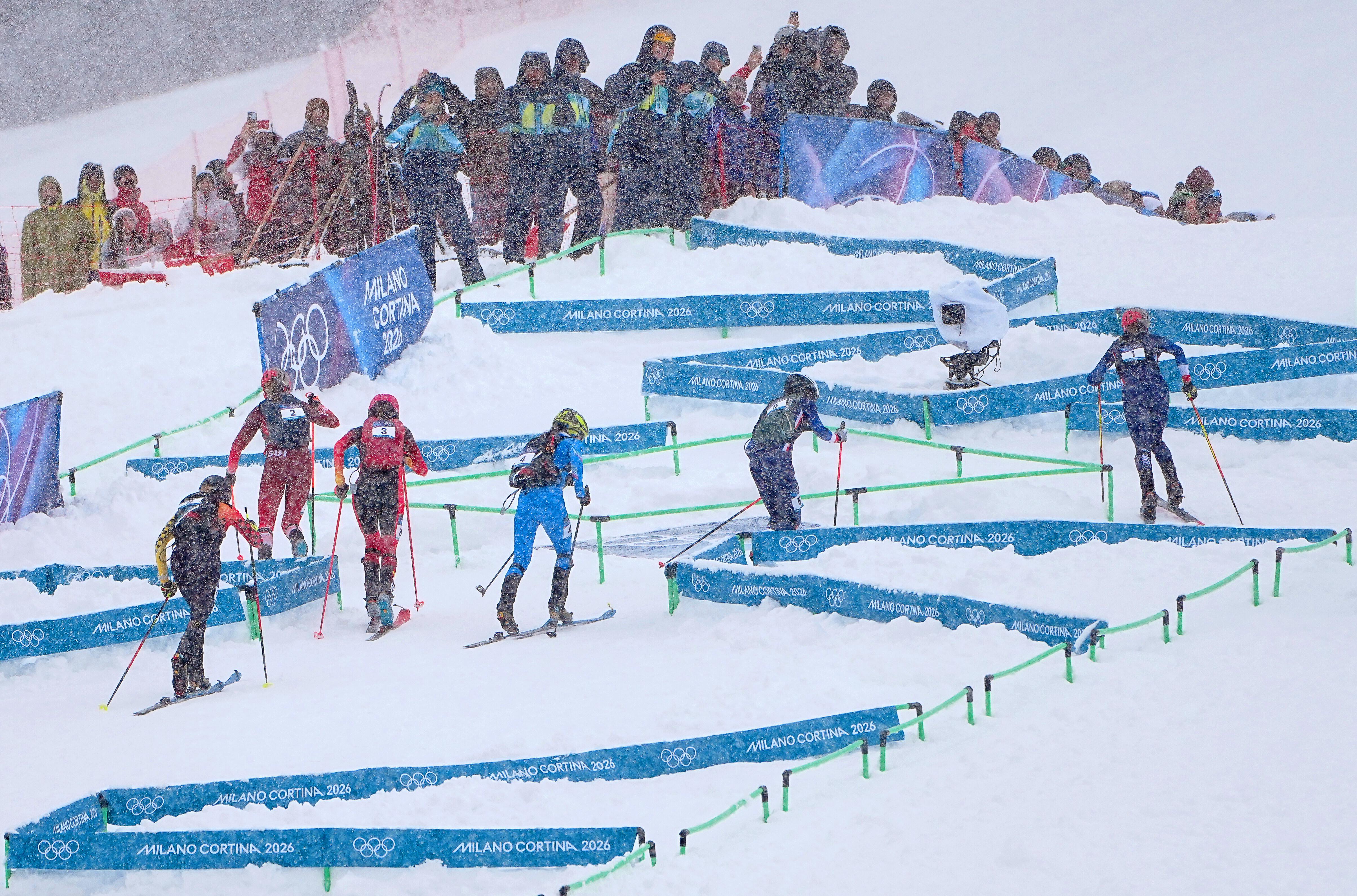 Skibergsteiger beim olympischen Wettbewerb, im Hintergrund einige Personen am Pistenrand, es schneit stark. (Archivbild)