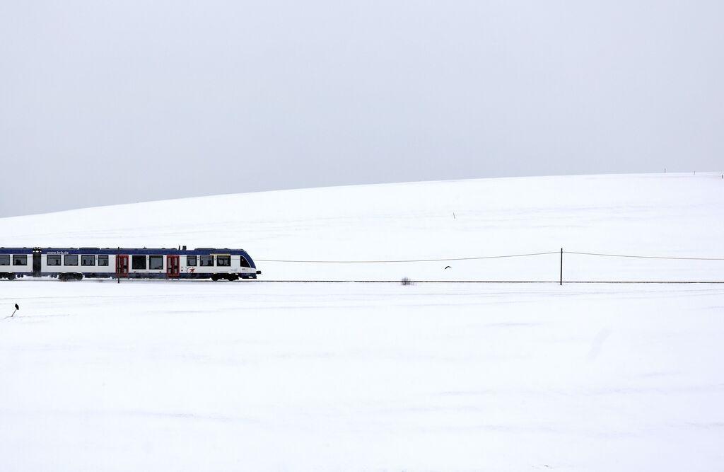 Bayern, Marktoberdorf: Ein Regionalzug fährt durch die tief verschneite Landschaft. 