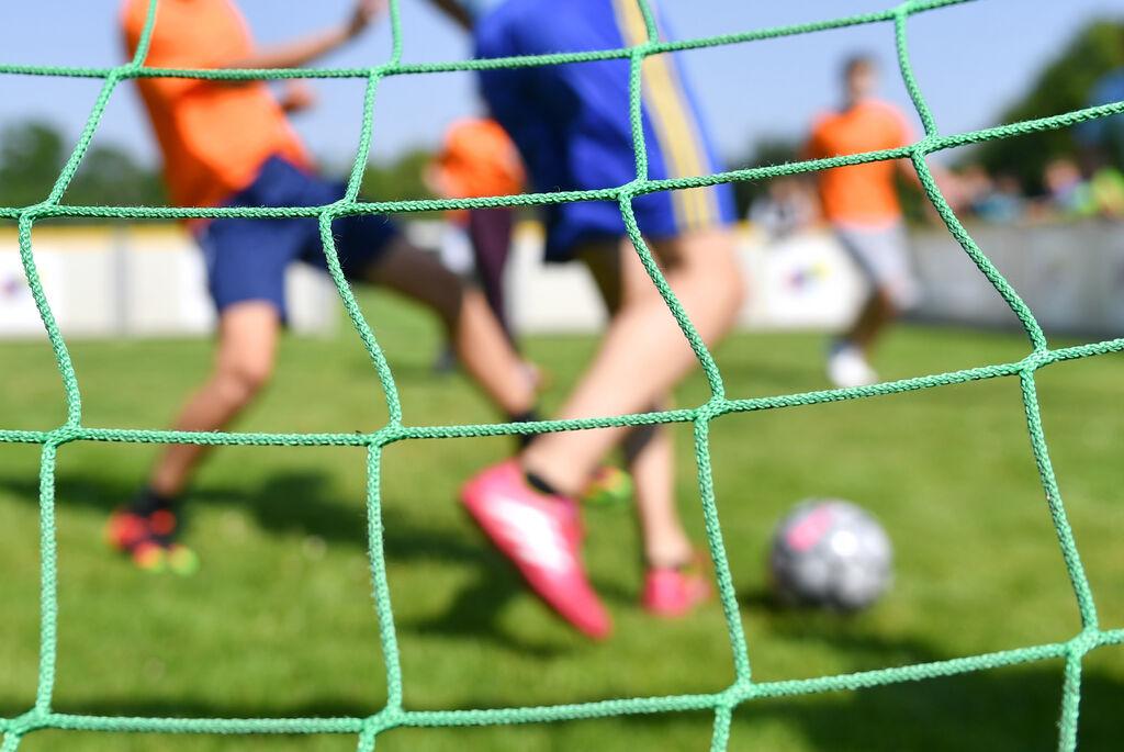Kinder spielen auf einem Sportplatz Fußball. (Symbolbild)
