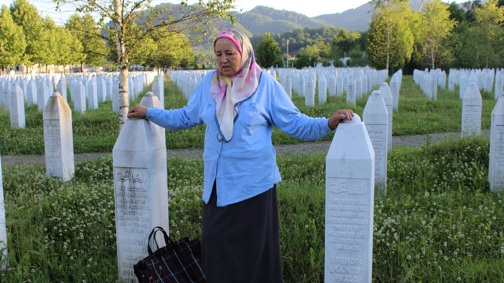 Man sieht eine Hinterbliebene auf dem Friedhof von Potocari bei Sarajevo zwischen Grabsteinen.