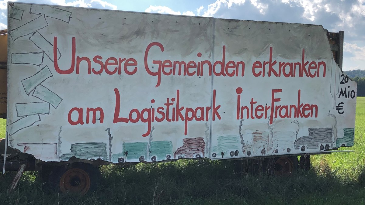 Transparent auf einer Wiese mit der Aufschrift "Unsere Gemeinden erkranken am Logistikpark Interfranken".