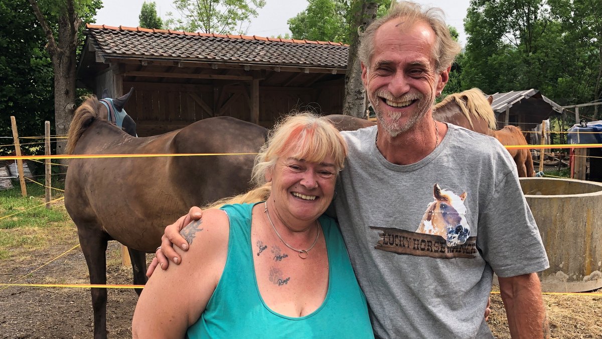 Die neue Lucky Horse Ranch in Weiching bei Tuntenhausen. Lisa und Koni Gradl stehen Arm in Arm vor einem Laufstall mit Pferden.