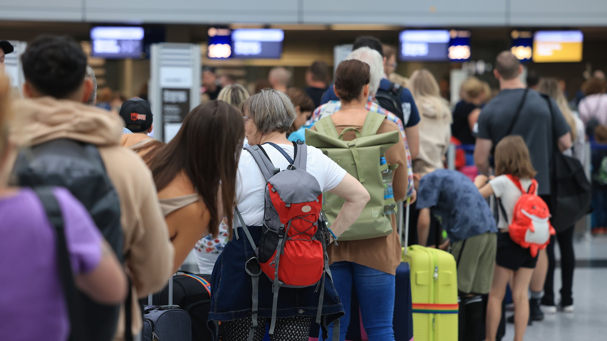 Reisende stehen am Flughafen in einer Warteschlange. 