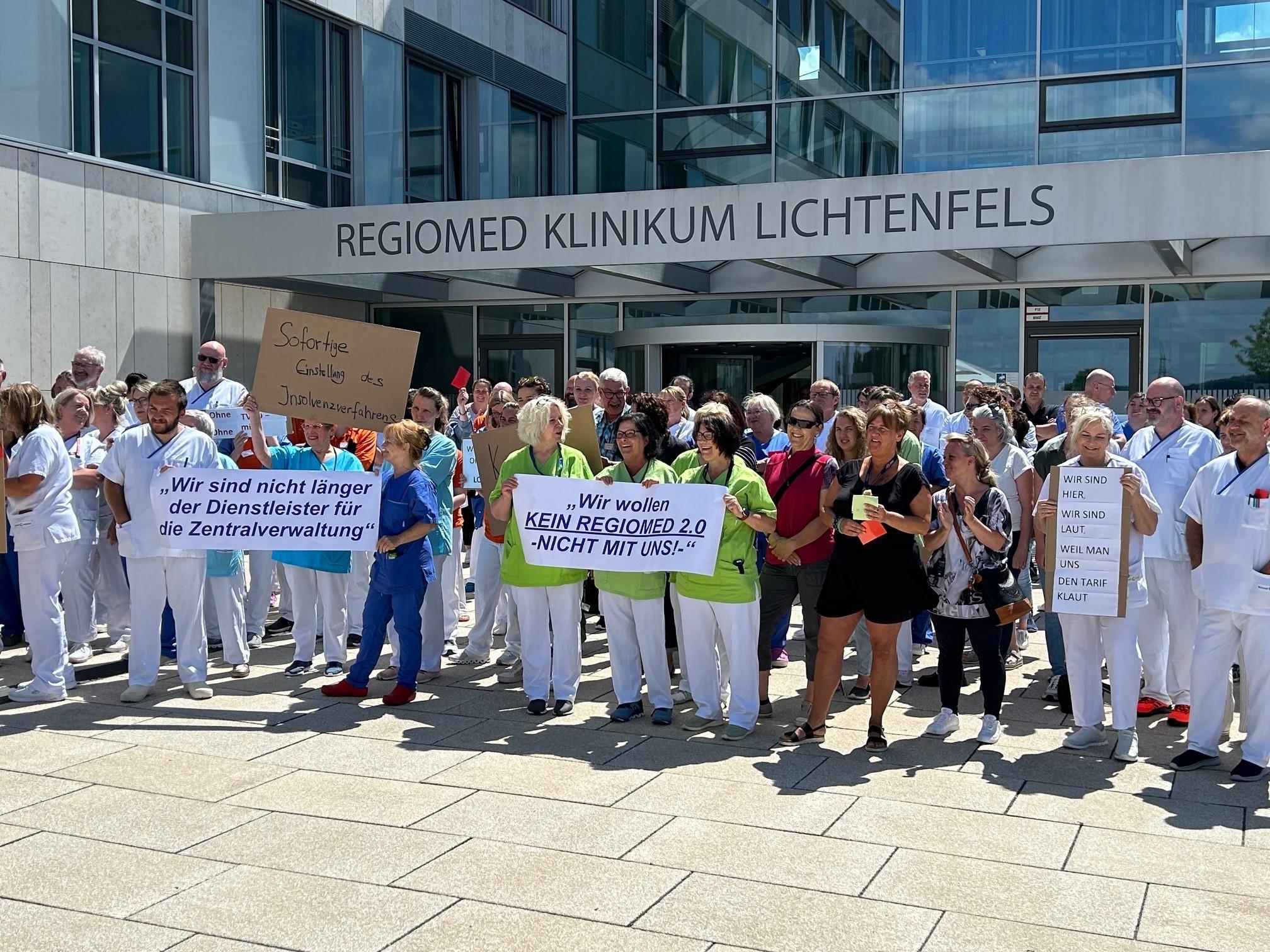 Mitarbeitende des Klinikums Lichtenfels demonstrieren mit Plakaten vor dem Gebäude ihres Arbeitgebers. 