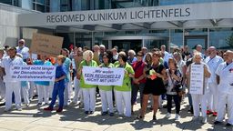 Mitarbeitende des Klinikums Lichtenfels demonstrieren mit Plakaten vor dem Gebäude ihres Arbeitgebers.  | Bild:BR/Andi Ebert