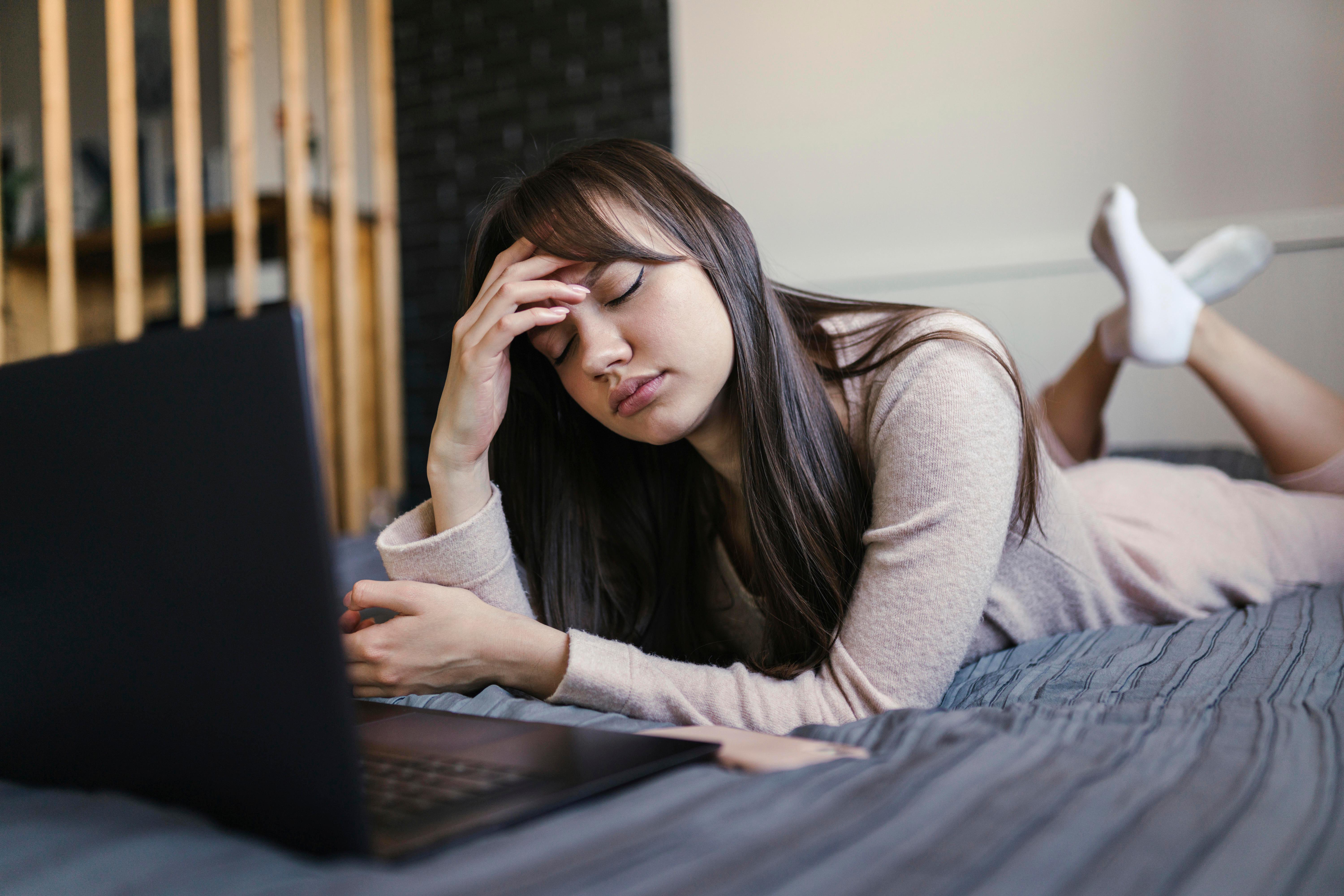 Symbolbild: Junge Frau mit Laptop auf dem Bett