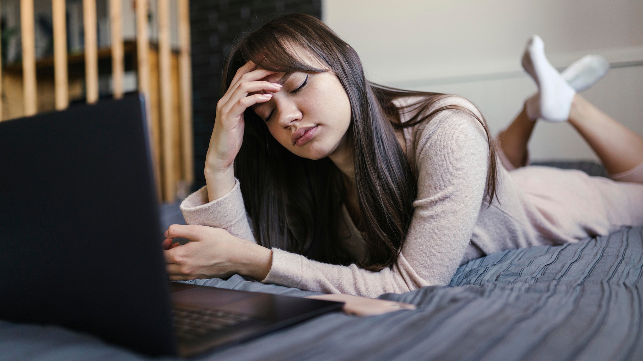 Symbolbild: Junge Frau mit Laptop auf dem Bett