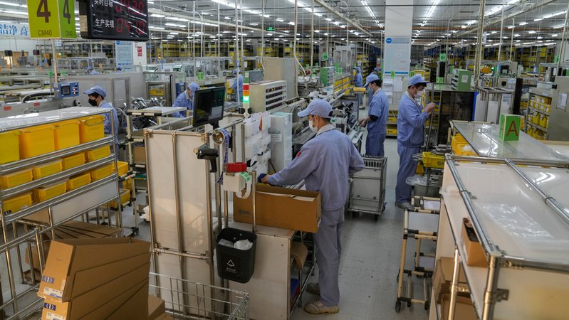Arbeiter mit Maske montieren Maschinenteile in der Fabrik von SMC China