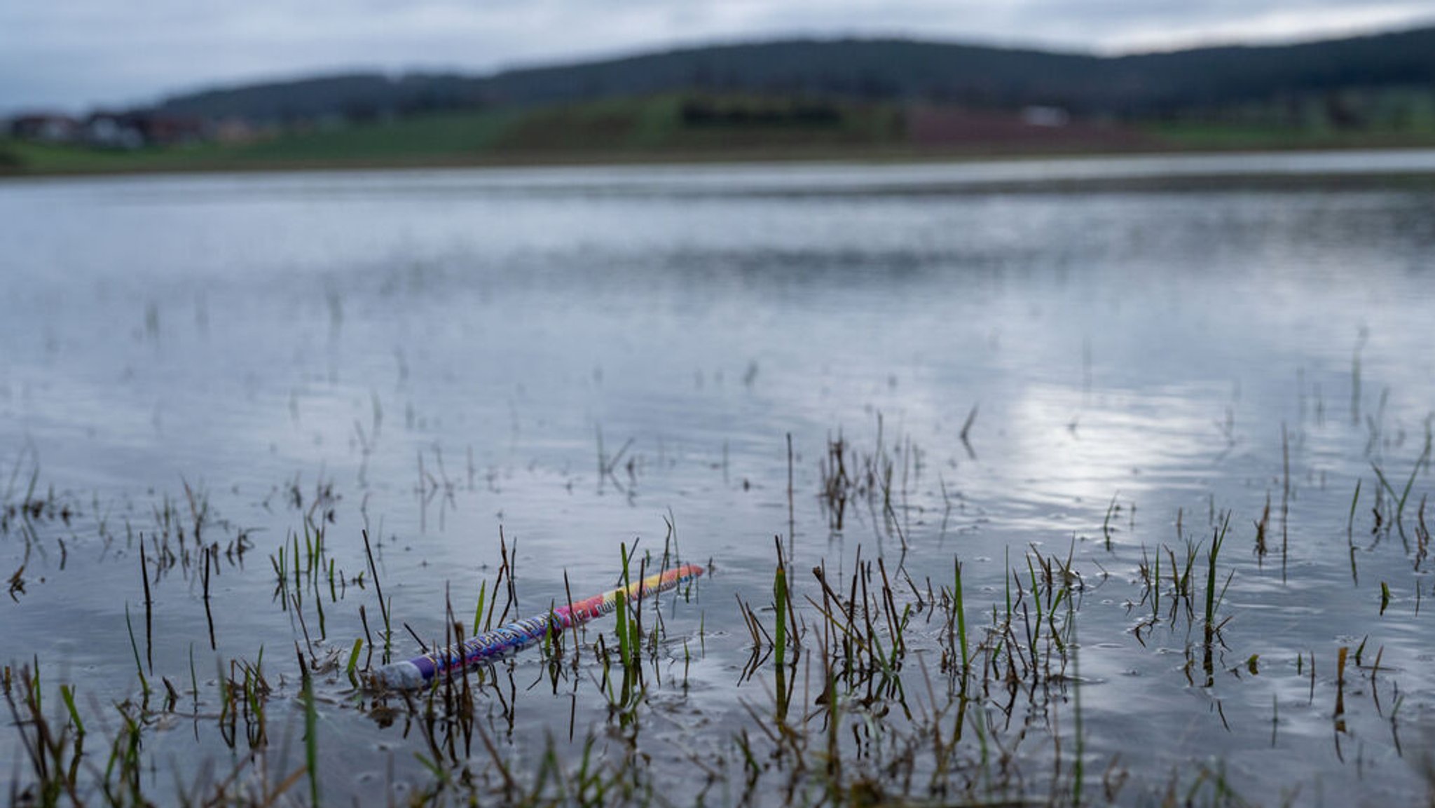 01.01.2024, Bayern, Gleusdorf: Die Reste von Silvester-Feuerwerk schwimmen am Rand einer überfluteten Wiese im Itzgrund.