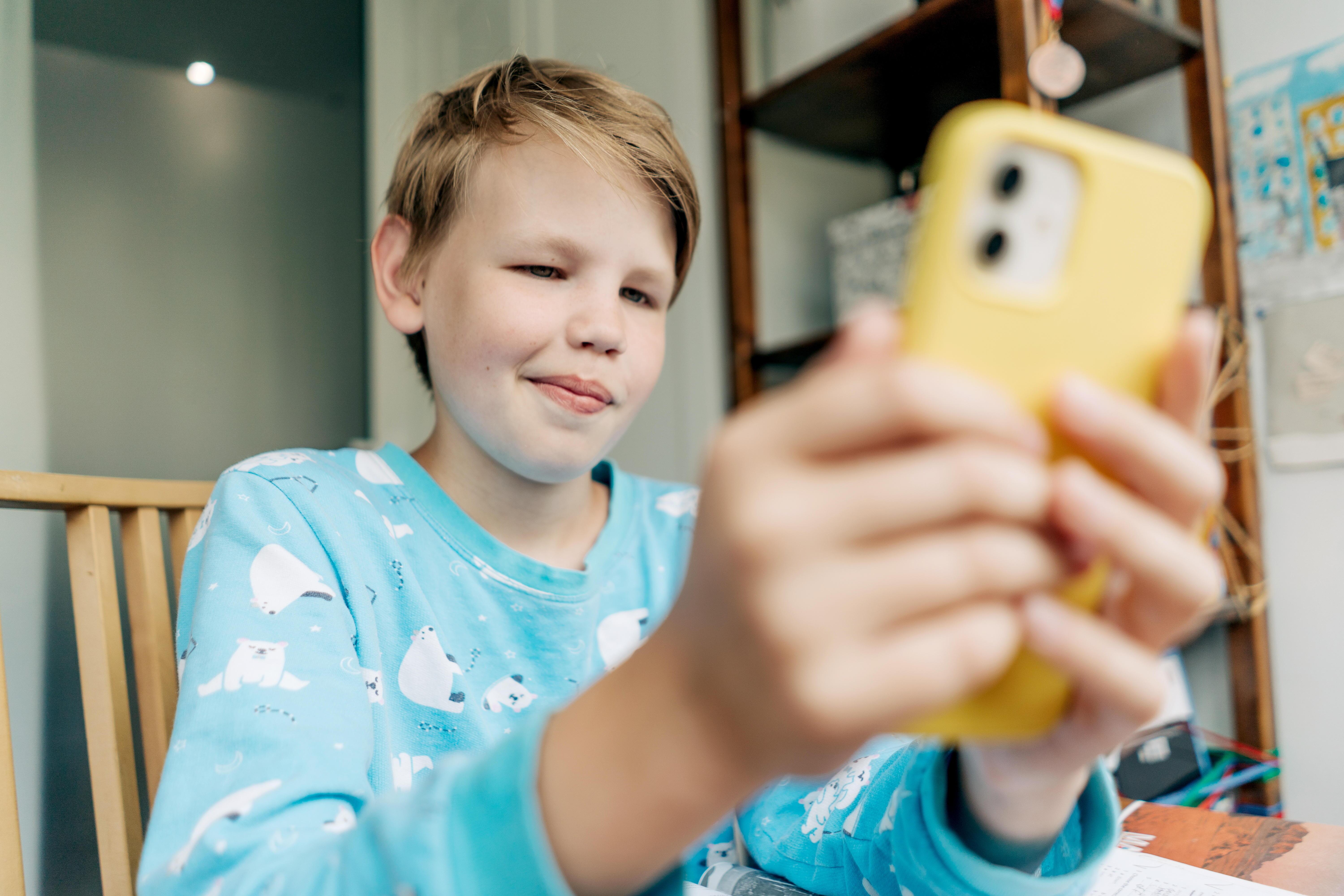 Ein Junge hat mit seinem Smartphone Zugang zum Internet. Damit Kinder und Jugendliche sich sicher im Internet bewegen, benötigen sie bestimmte Kompetenzen. Die Uni Mannheim hat die wichtigsten Fähigkeiten, die junge Internetnutzer brauchen, erarbeitet.