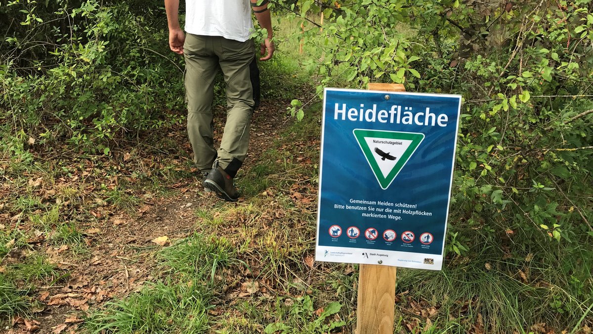 Schild macht auf das Naturschutzgebiet Augsburger Heideflächen aufmerksam.