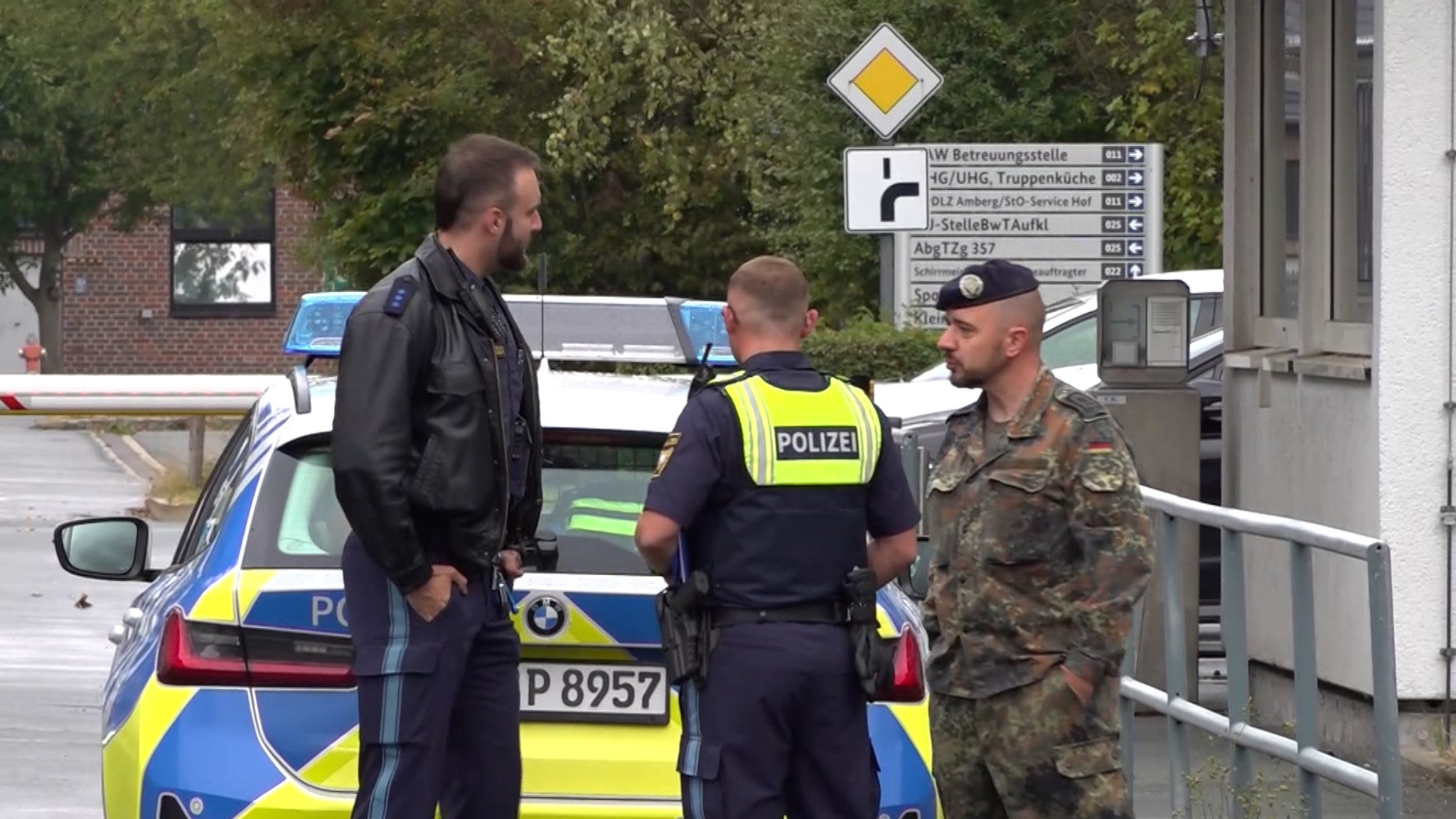 Polizisten und ein Soldat stehen neben einem Polizeiauto