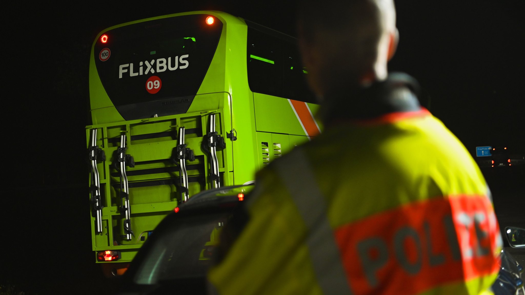 Ein Polizist schaut an einer Kontrollstelle einem Bus des Unternehmens Flixbus hinterher.