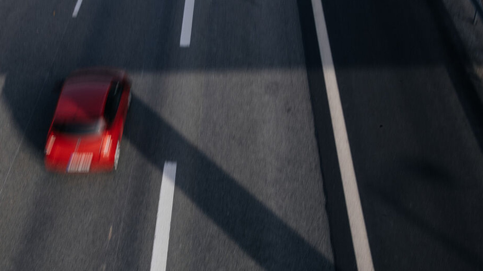 Ein rotes Auto fährt auf einer mehrspurigen Straße