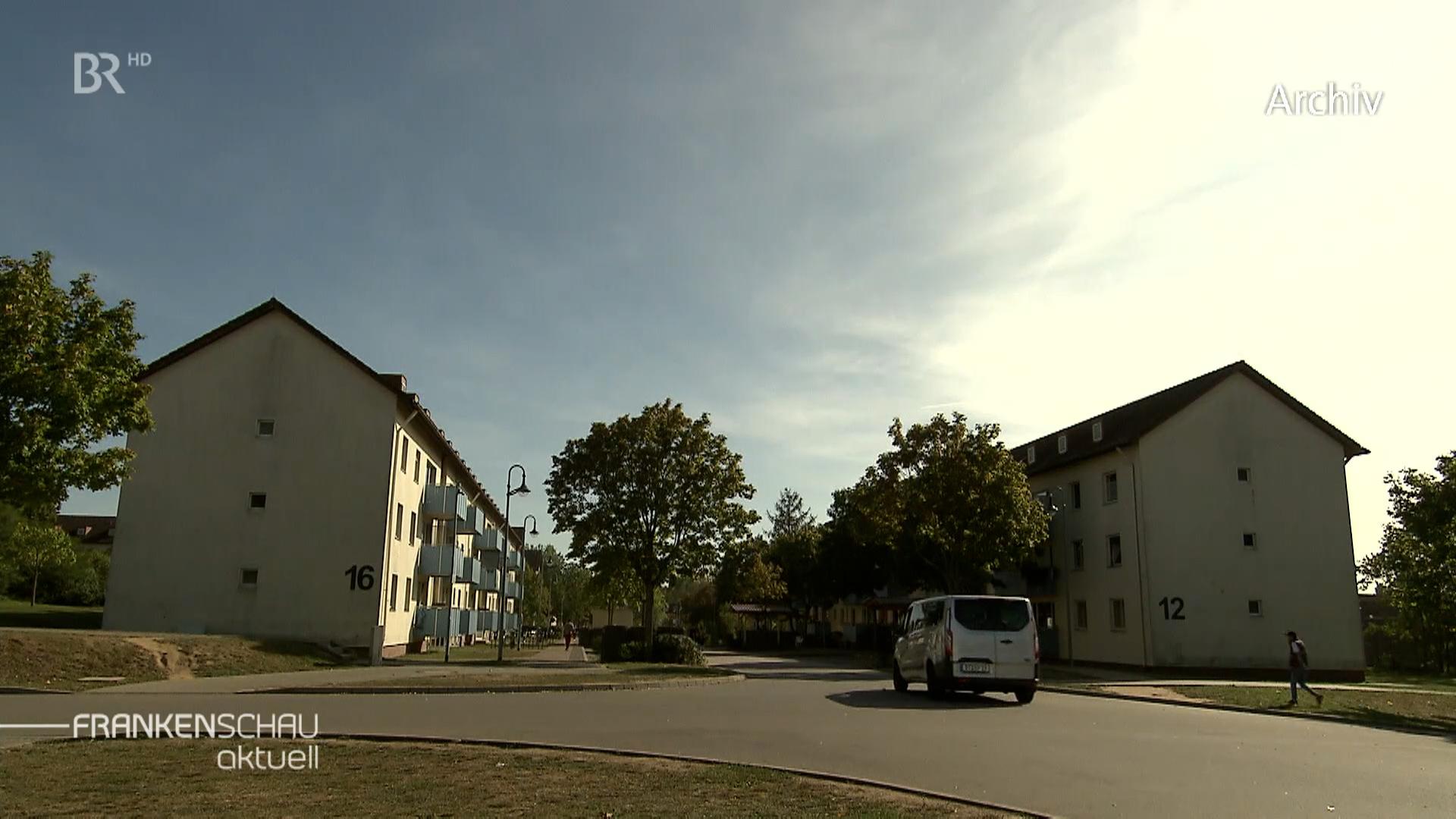 Zwei langgezogene Reihenhäuser mit Bäumen dazwischen. 