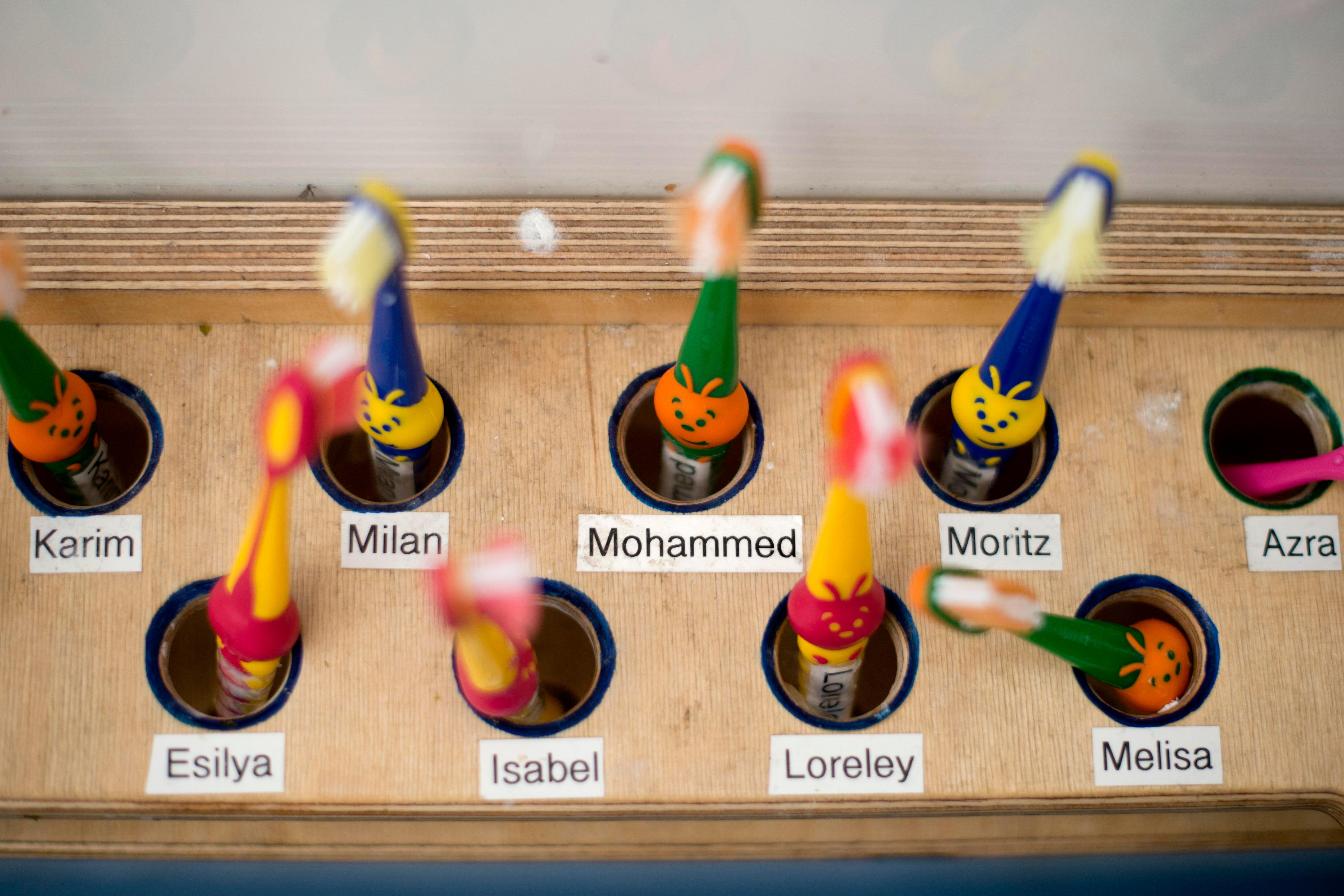 Namensschilder an einem Ständer für Zahnbürsten in einer Kita. Kinder, die mehrsprachig aufwachsen oder zu Hause wenig Deutsch sprechen, profitieren besonders von früher Förderung in Kita und Schule.