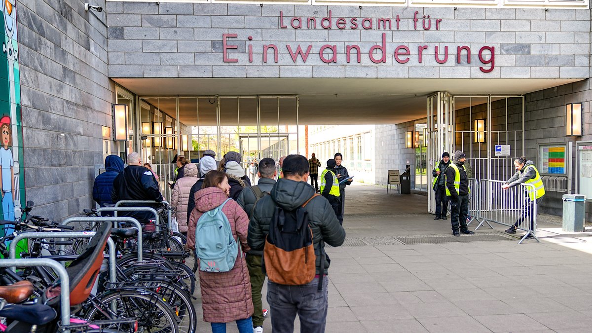 Menschen stehen in einer Schlange vor dem Landesamt für Einwanderung in Berlin