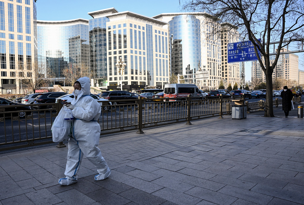 Eine Frau in Schutzkleidung läuft eine Straße in Beijing am 26. Dezember 2022 entlang.