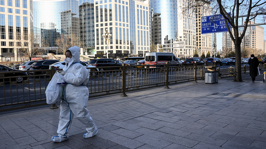 Eine Frau in Schutzkleidung läuft eine Straße in Beijing am 26. Dezember 2022 entlang.