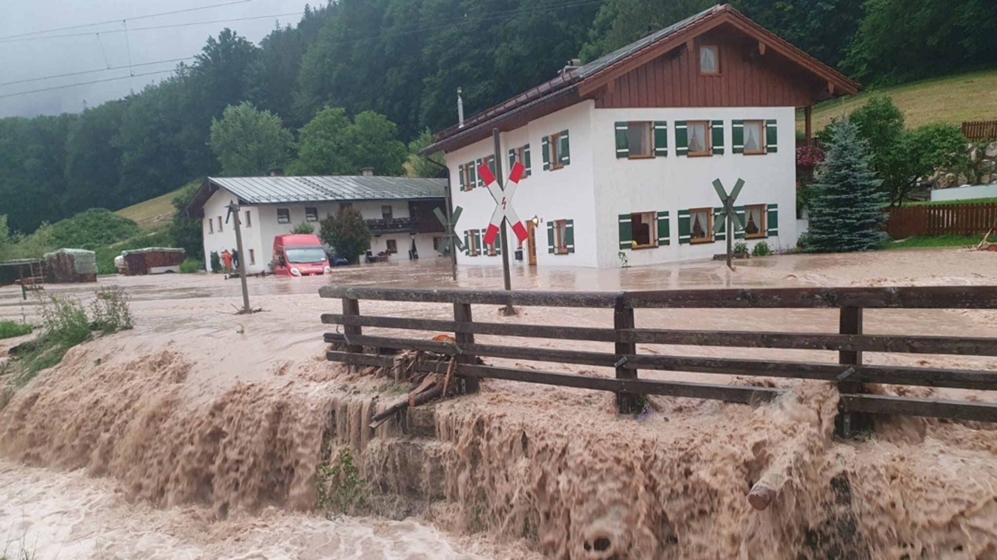 ARCHIV - 17.07.2021, Bayern, Bischofswiesen: Wasser fließt über einen Platz vor einem Haus.