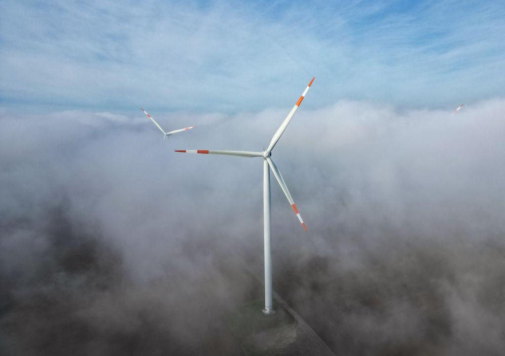 ARCHIV - 18.10.2023, Sachsen-Anhalt, Querfurt: Die Windräder in einem Windpark ragen aus dem Morgennebel hervor. Kommunen sollen unbürokratischer am Ausbau von erneuerbaren Energien beteiligt werden. (Luftaufnahme mit Drohne) (zu dpa: «Kommunen sollen am Ausbau von Erneuerbaren beteiligt werden») Foto: Jan Woitas/dpa +++ dpa-Bildfunk +++