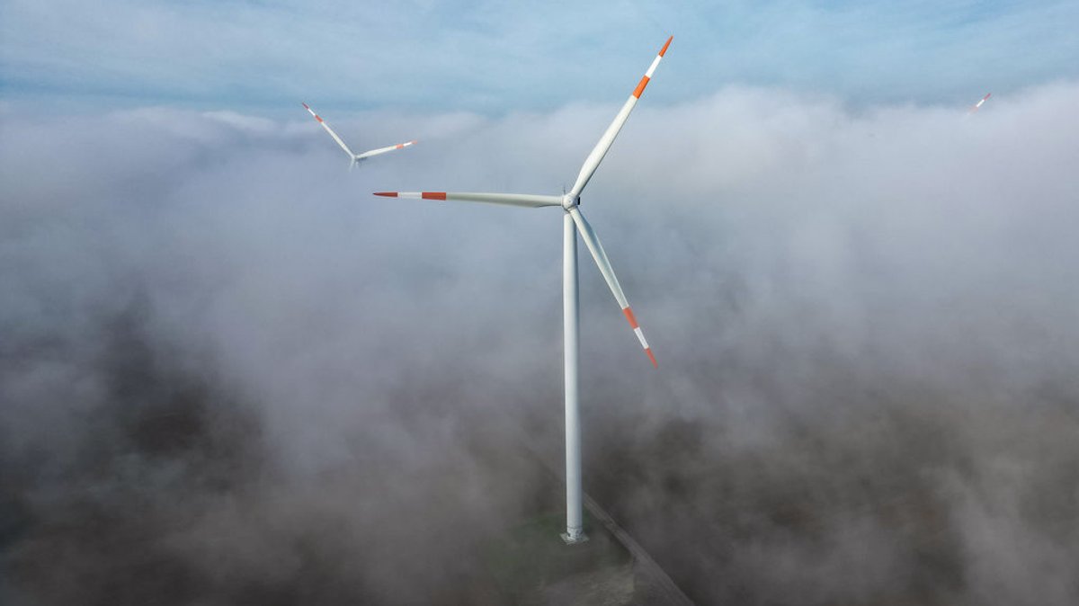 ARCHIV - 18.10.2023, Sachsen-Anhalt, Querfurt: Die Windräder in einem Windpark ragen aus dem Morgennebel hervor. Kommunen sollen unbürokratischer am Ausbau von erneuerbaren Energien beteiligt werden. (Luftaufnahme mit Drohne) (zu dpa: «Kommunen sollen am Ausbau von Erneuerbaren beteiligt werden») Foto: Jan Woitas/dpa +++ dpa-Bildfunk +++