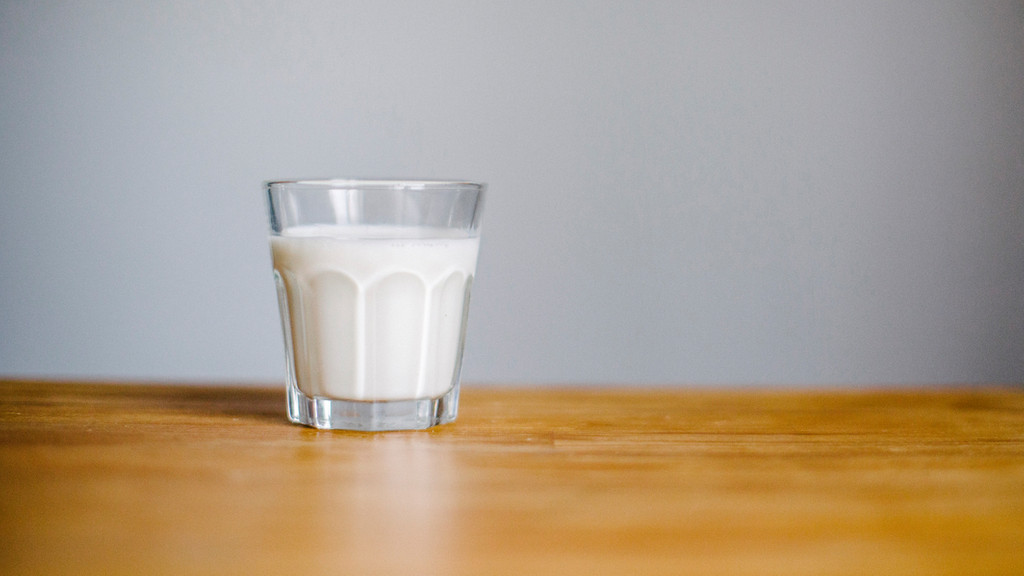 Ein Glas Milch, abgestellt auf einem Holztisch