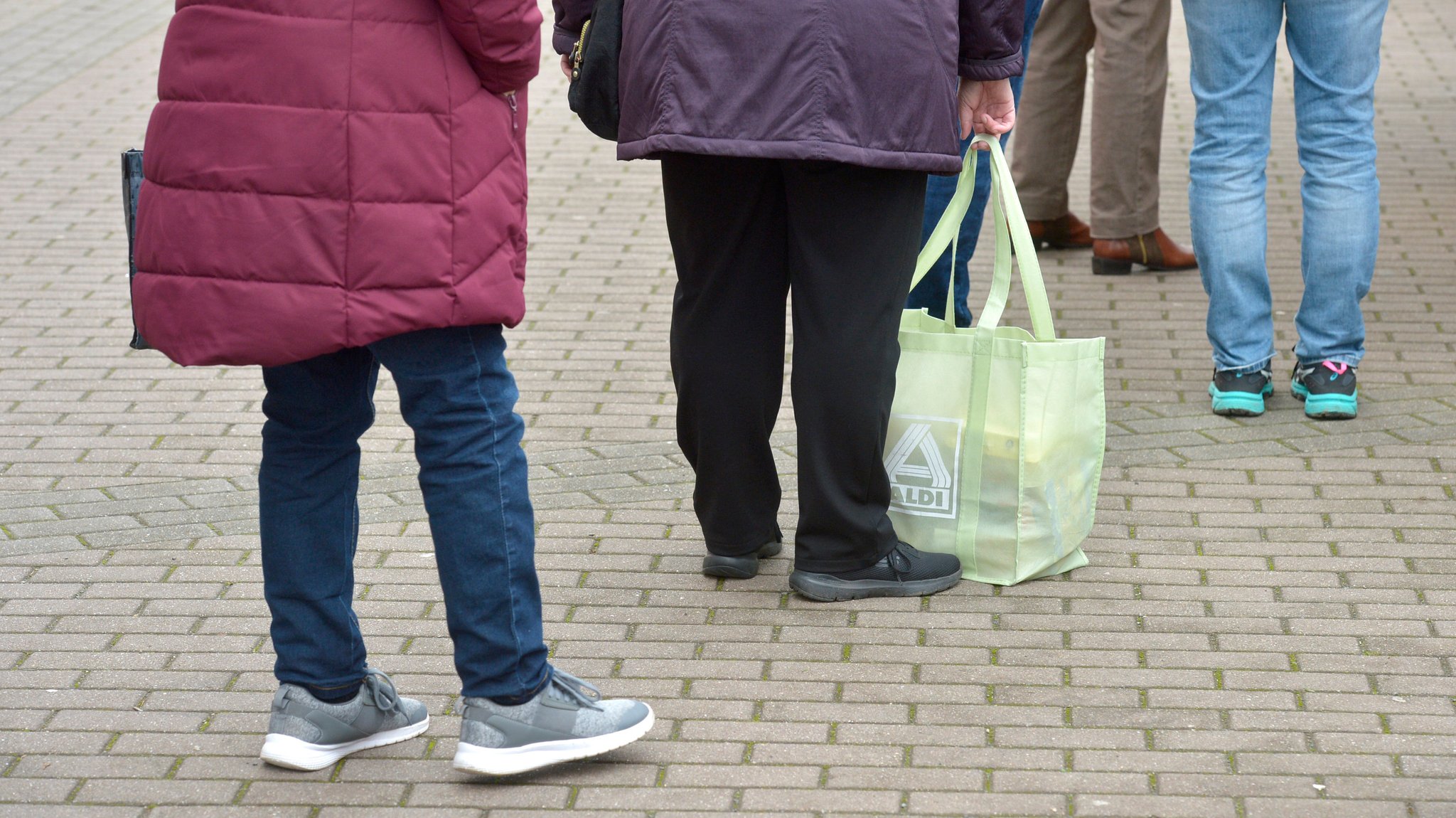 In einer kleinen Schlange stehen Menschen mit Abstand auf der Straße an.