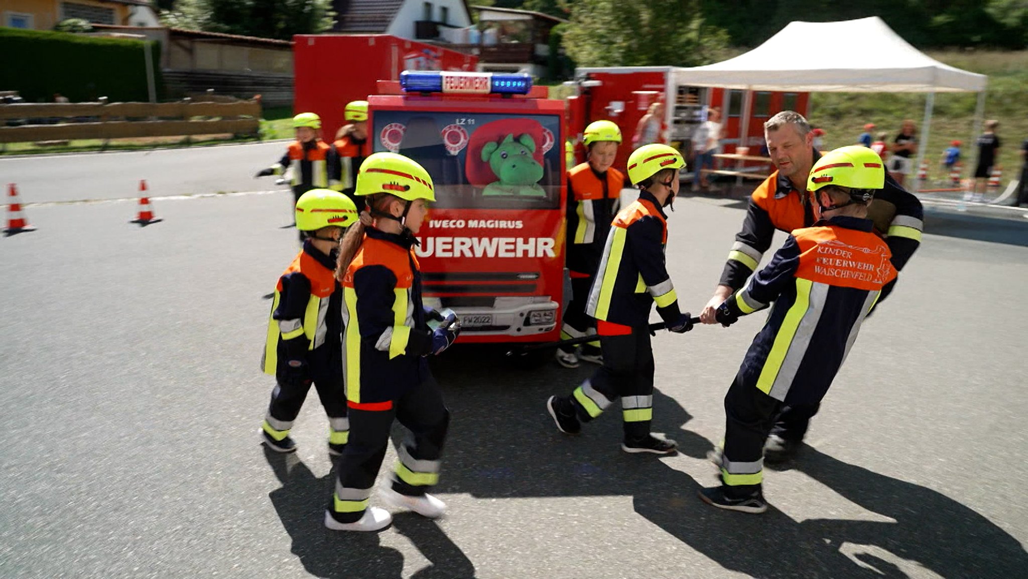 Kinder simulieren an einem Miniatur-Feurwehrauto einen EInsatz.