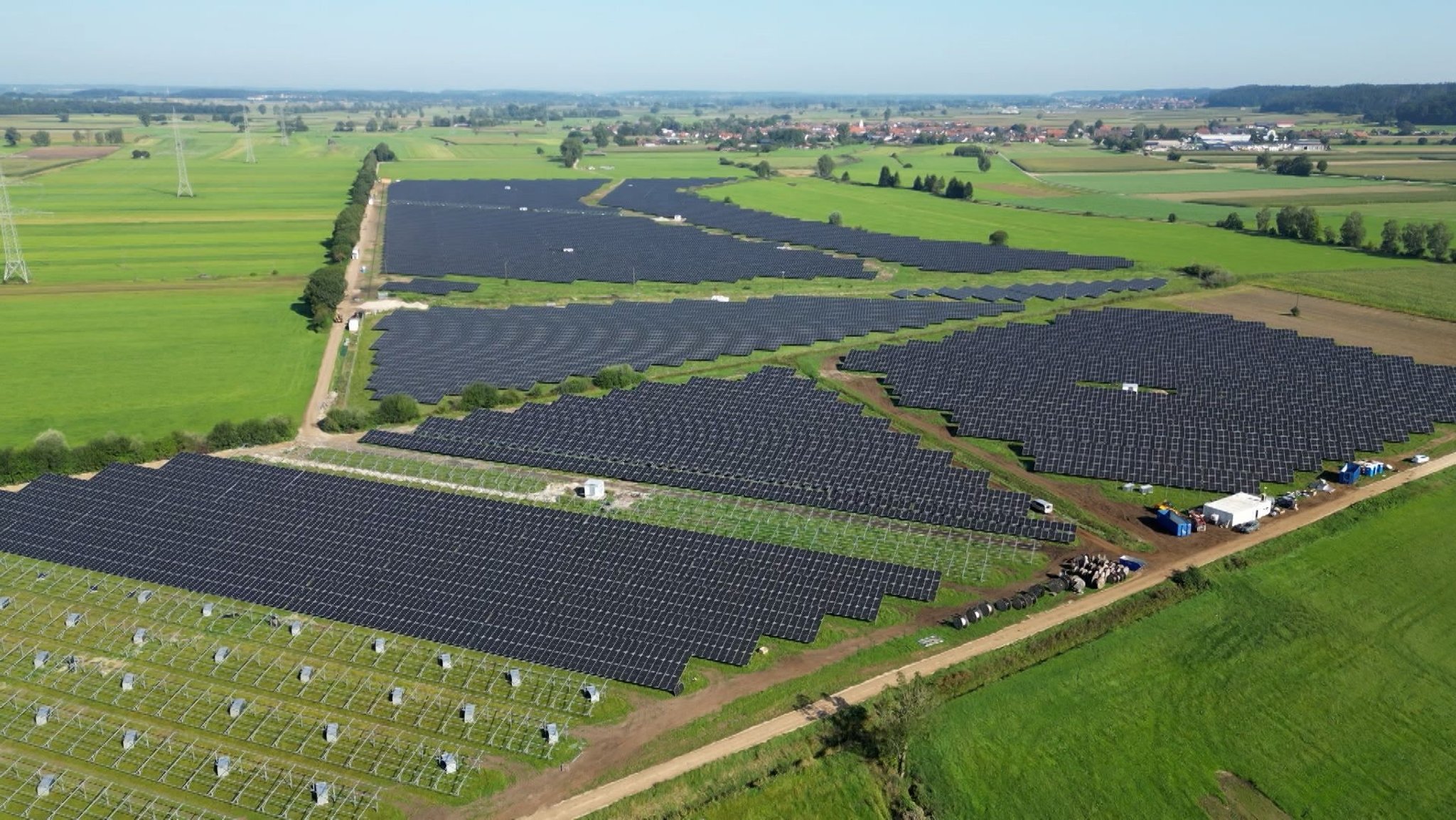 Der große Solarpark zwischen Oberroth und Unterroth im Landkreis Neu-Ulm aus der Luftperspektive. Grüne Wiesen umgeben die schwarzen PV-Module.