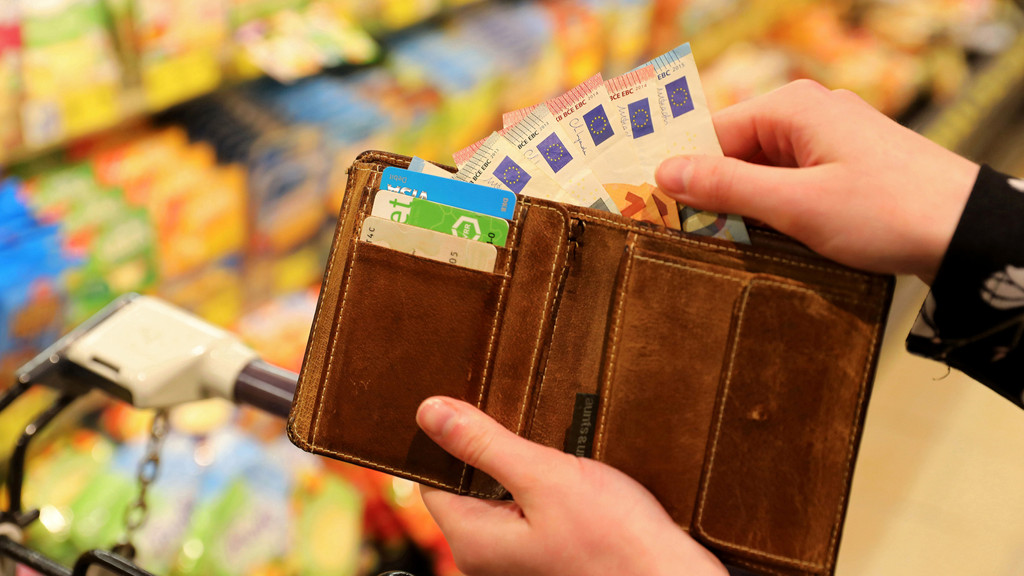 Jemand hält in einem Supermarkt Geldscheine in der Hand (Symbolbild)