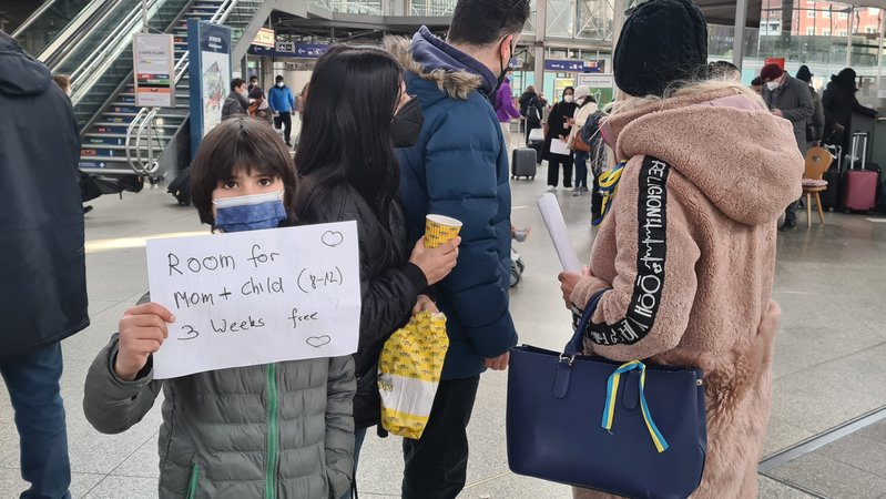 Eine junge Familie steht am Münchner Hauptbahnhof und wartet auf den nächsten Zug mit Kriegsflüchtlingen. Sie wollen ihnen eine Unterkunft bieten
