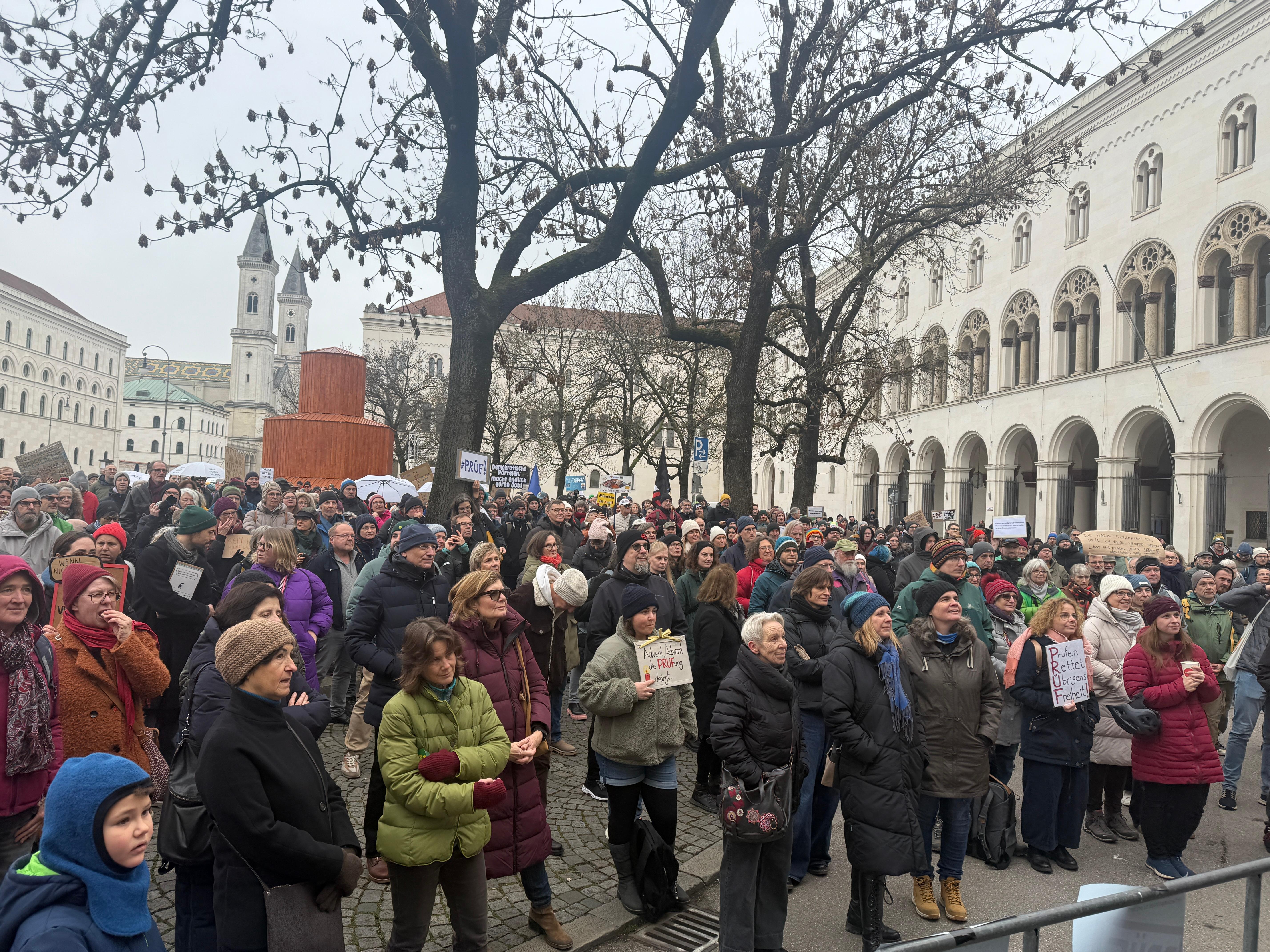 Mehrere Menschen mit Plakaten stehen vor dem Hauptgebäude der Ludwig-Maximilians-Universität.
