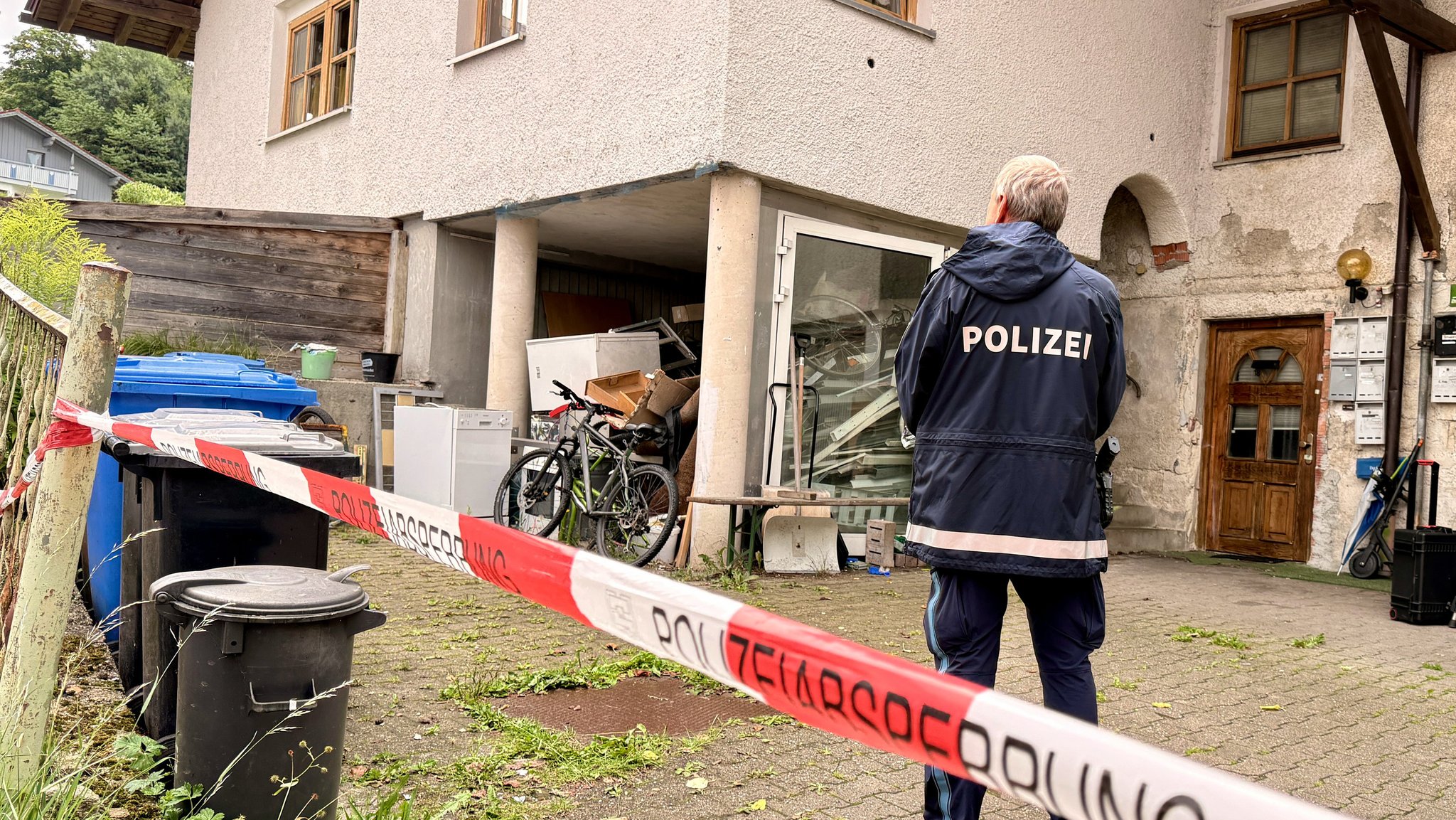 Ein Polizist steht vor dem Haus in Zwiesel, in dem drei Leichen gefunden worden waren. | Bild: dpa-Bildfunk/Christine Vincon Ein Polizist steht vor dem Haus in Zwiesel, in dem drei Leichen gefunden worden waren.