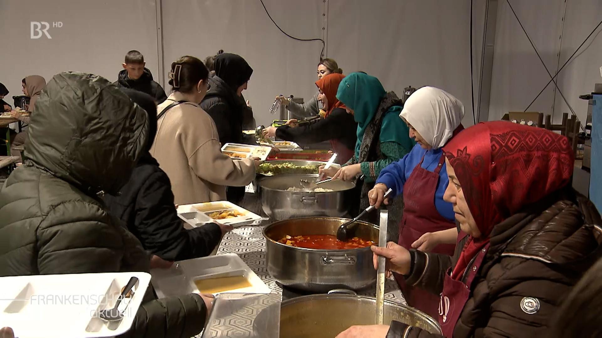 Frauen verteilen Essen an der Essensausgabe.