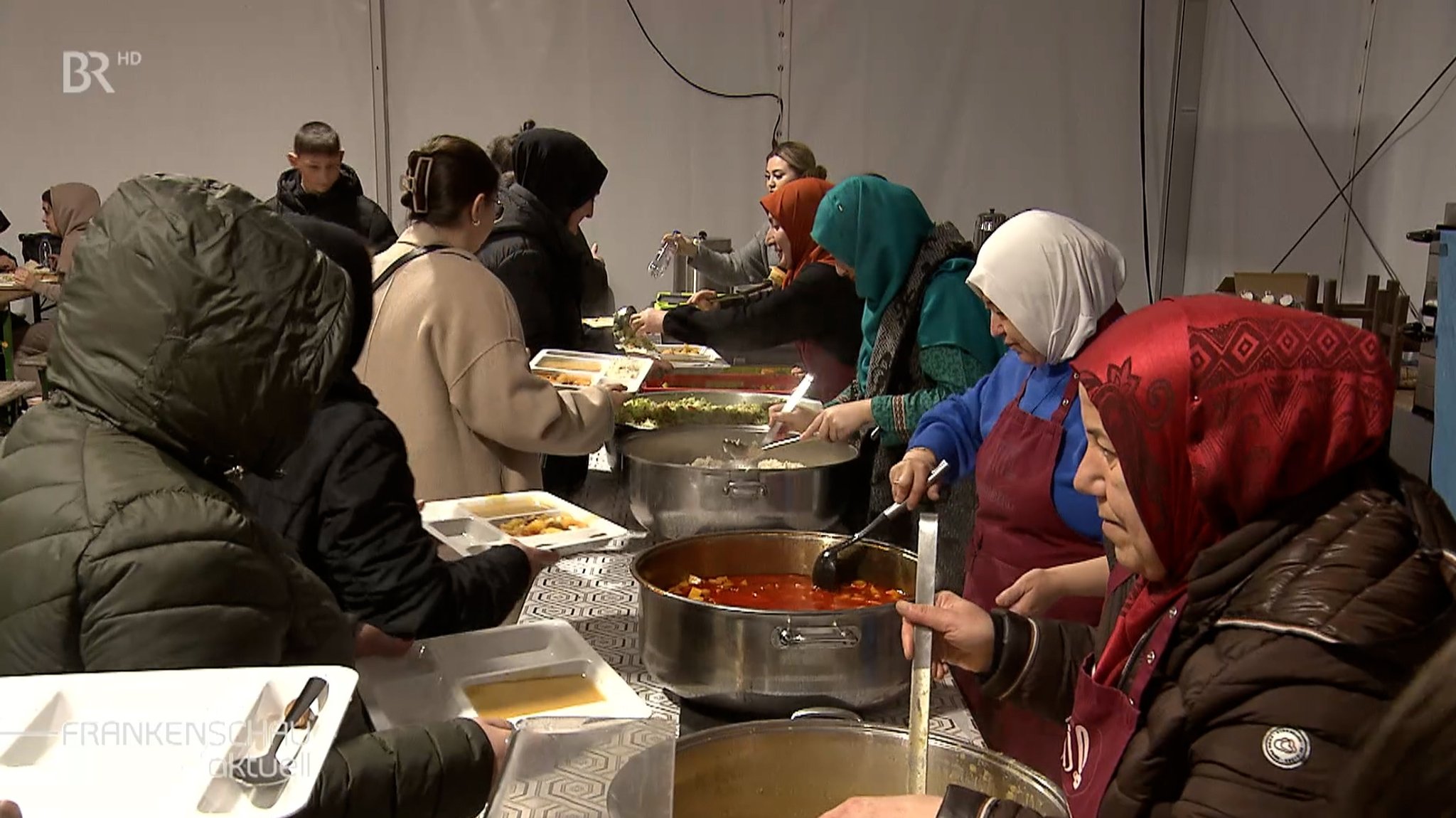 Frauen verteilen Essen an der Essensausgabe.