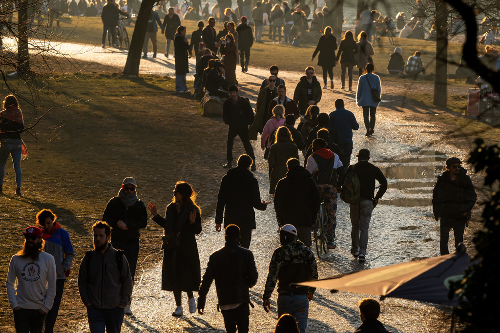 Menschen laufen an der Münchner Isar durch die Sonne.