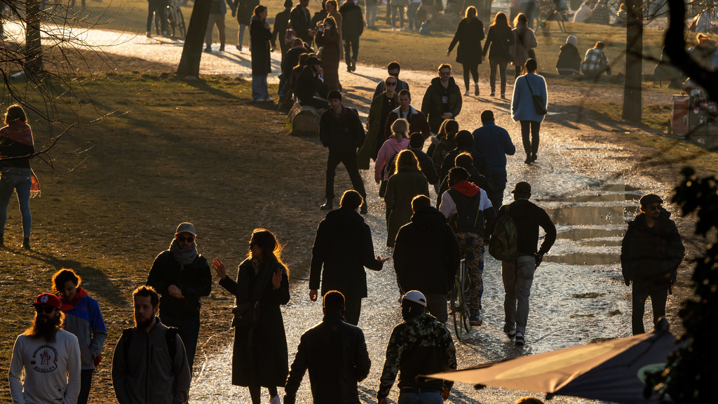 Menschen laufen an der Münchner Isar durch die Sonne.