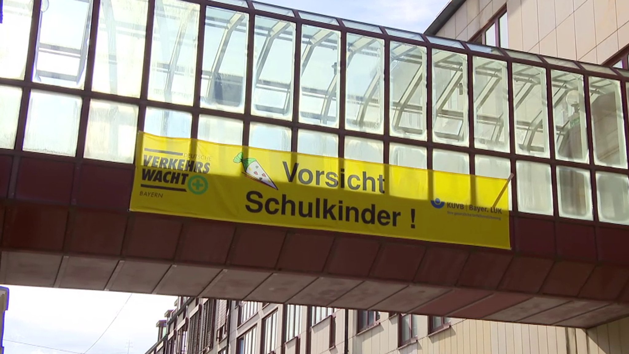 "Vorsicht Schulkinder" steht auf einem gelben Banner, dass an der Glasfassade eines Gebäudes hängt.