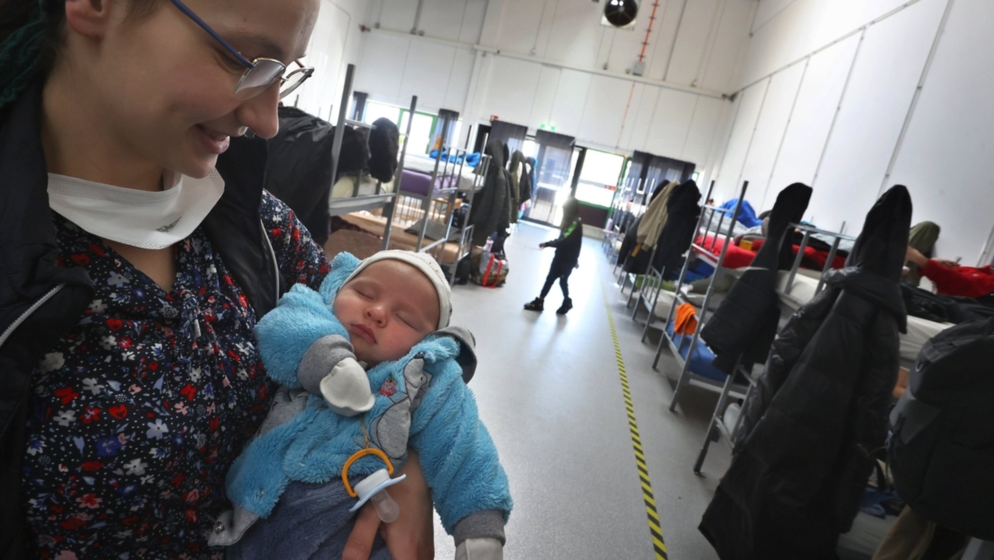 Eine geflüchtete Frau aus der Ukraine hält im Schlafsaal des ANKER Zentrums in Augsburg ihr Baby auf dem Arm. 