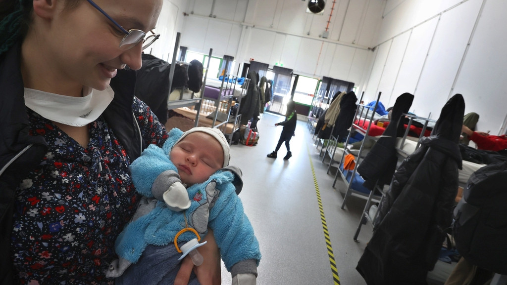 Eine geflüchtete Frau aus der Ukraine hält im Schlafsaal des ANKER Zentrums in Augsburg ihr Baby auf dem Arm. 