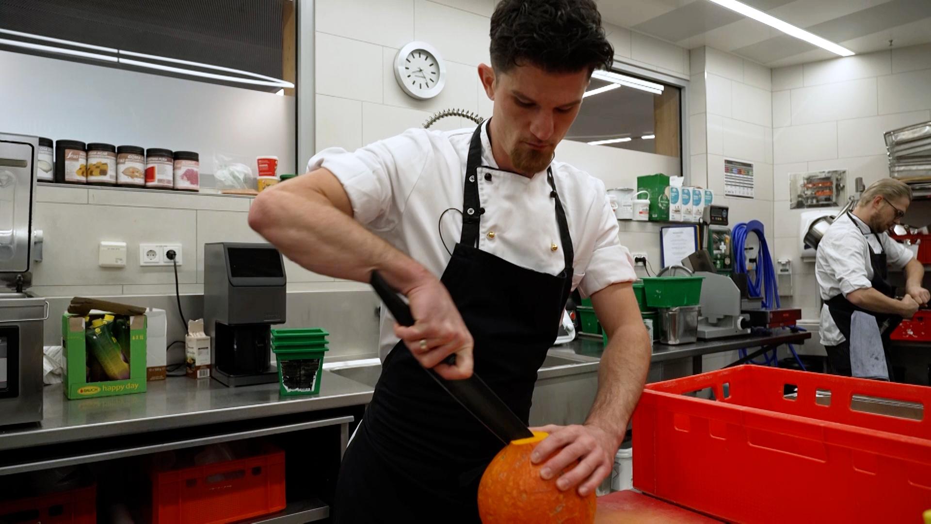 Ein Koch zerkleinert einen Kürbis in der Küche auf der Zugspitze