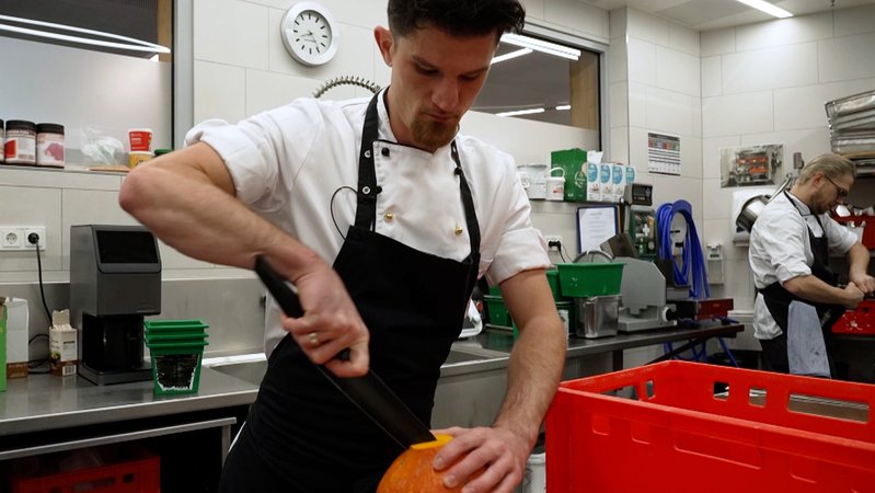 Ein Koch zerkleinert einen Kürbis in der Küche auf der Zugspitze | Bild: BR / Melina Eisemann Ein Koch zerkleinert einen Kürbis in der Küche auf der Zugspitze