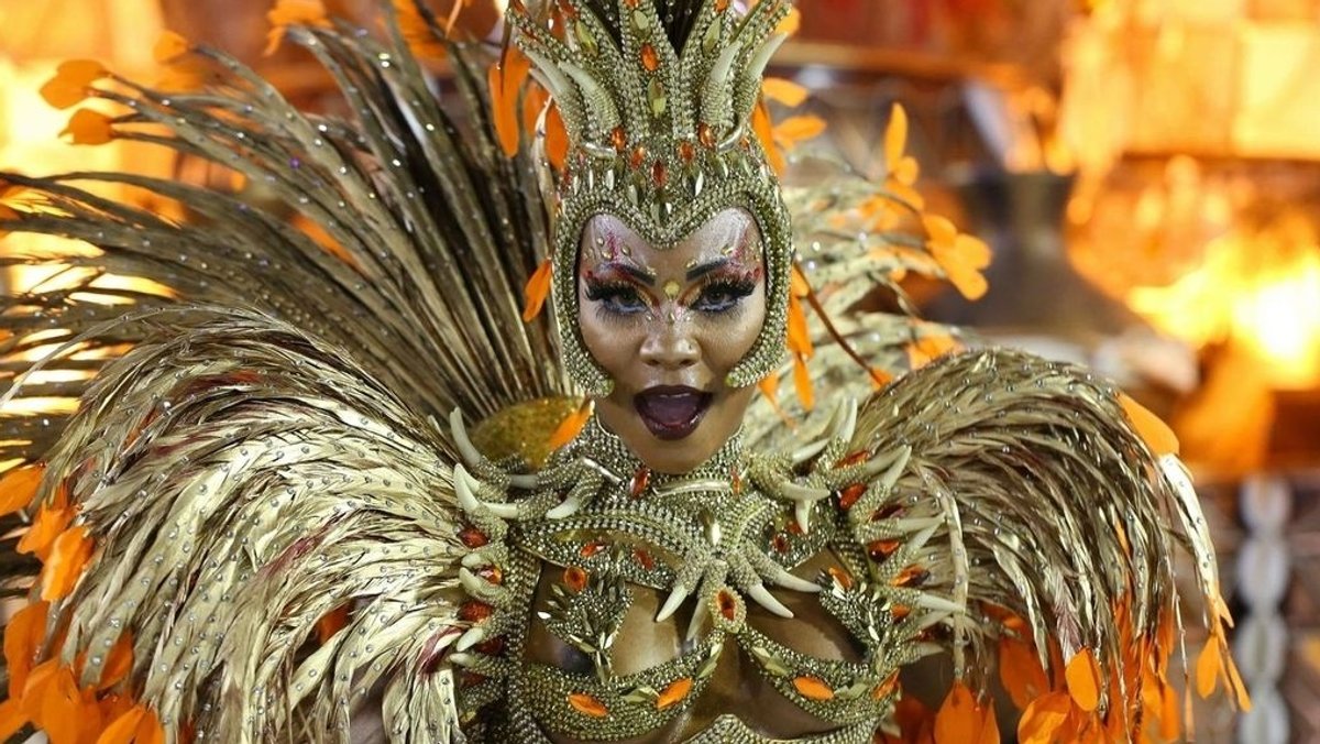 Eine Samba-Tänzerin und Künstlerin in einem goldfarbigen Feder-Kostüm.