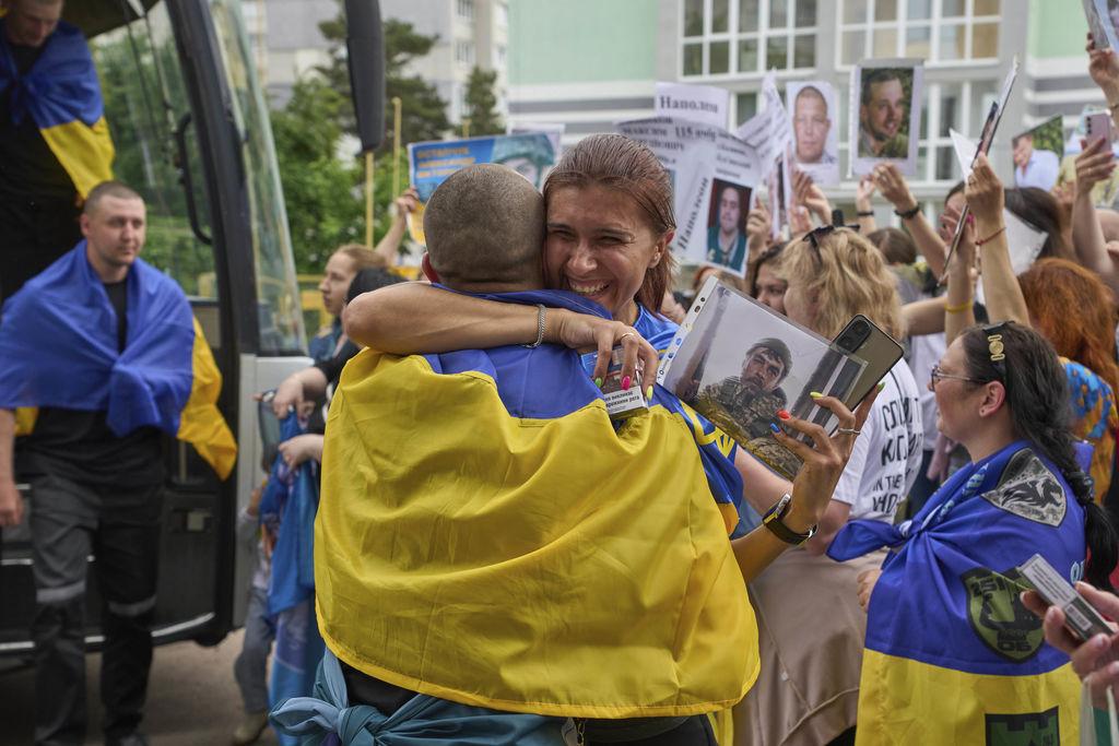 25.05.2025, Ukraine, Tschernihiw: Eine Frau umarmt einen Soldaten, der im Rahmen eines Kriegsgefangenenaustauschs zwischen Russland und der Ukraine am Sonntag, 25. Mai 2025 in der Region Tschernihiw aus der Gefangenschaft zurückgekehrt ist. Im Hintergrund zeigen Menschen Fotos von vermissten Soldaten. Russland und die Ukraine haben nach Angaben des russischen Verteidigungsministeriums ihren bisher größten Gefangenenaustausch abgeschlossen und jeweils weitere 303 Menschen freigelassen. Foto: Efrem Lukatsky/AP/dpa +++ dpa-Bildfunk +++