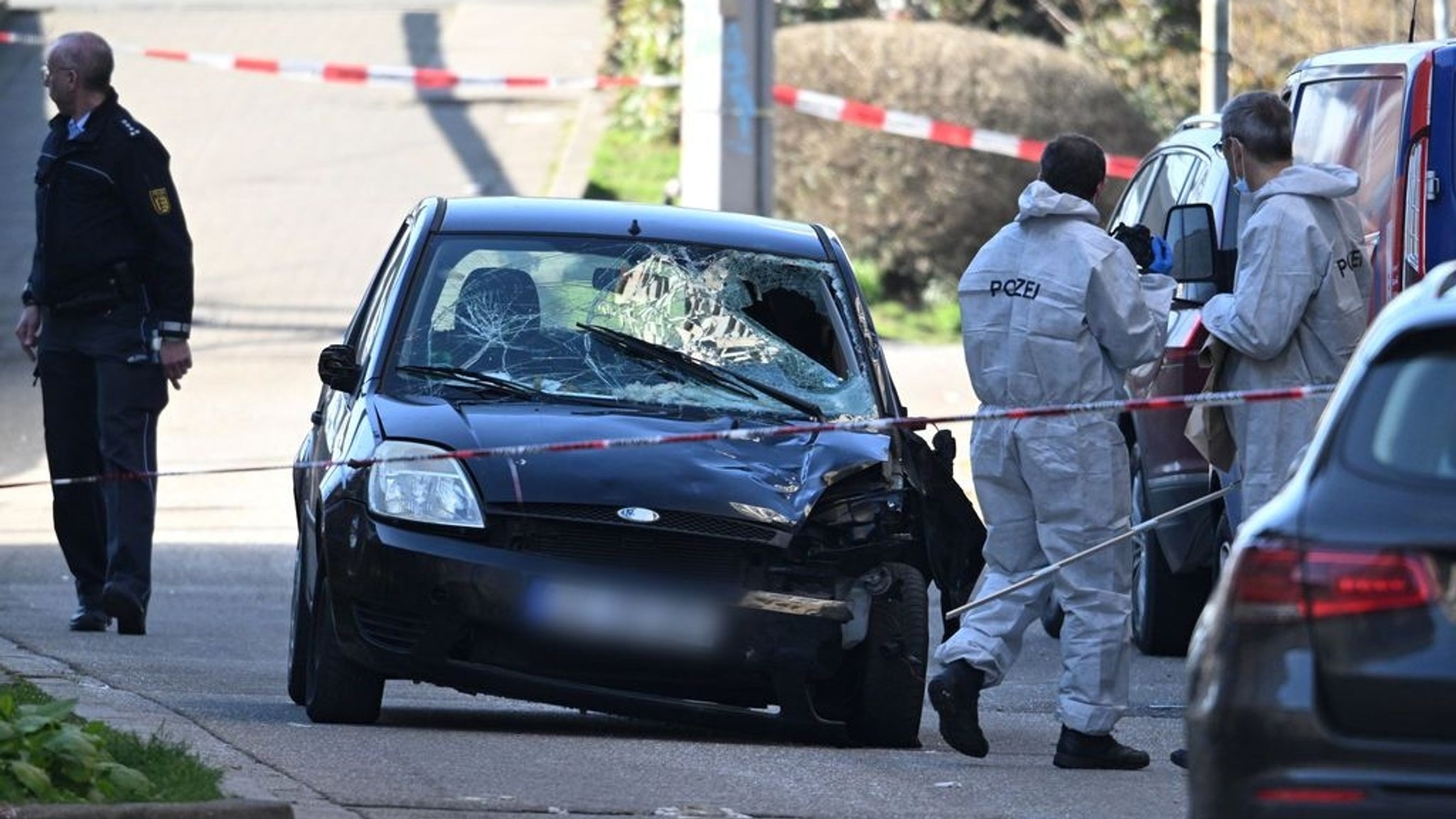 03.03.2025, Baden-Württemberg, Mannheim: Beamte der Spurensicherung untersuchen ein beschädigtes Fahrzeug an einer Zufahrt zur Rheinbrücke. Nach einem Vorfall mit einem Auto in der Mannheimer Innenstadt mit mindestens einem Toten und mehreren Verletzten ist der mutmaßliche Fahrer nach Polizeiangaben festgenommen worden. Nach Polizeiangaben war ein Fahrzeug in eine Menschenmenge gefahren. Foto: Boris Roessler/dpa +++ dpa-Bildfunk +++