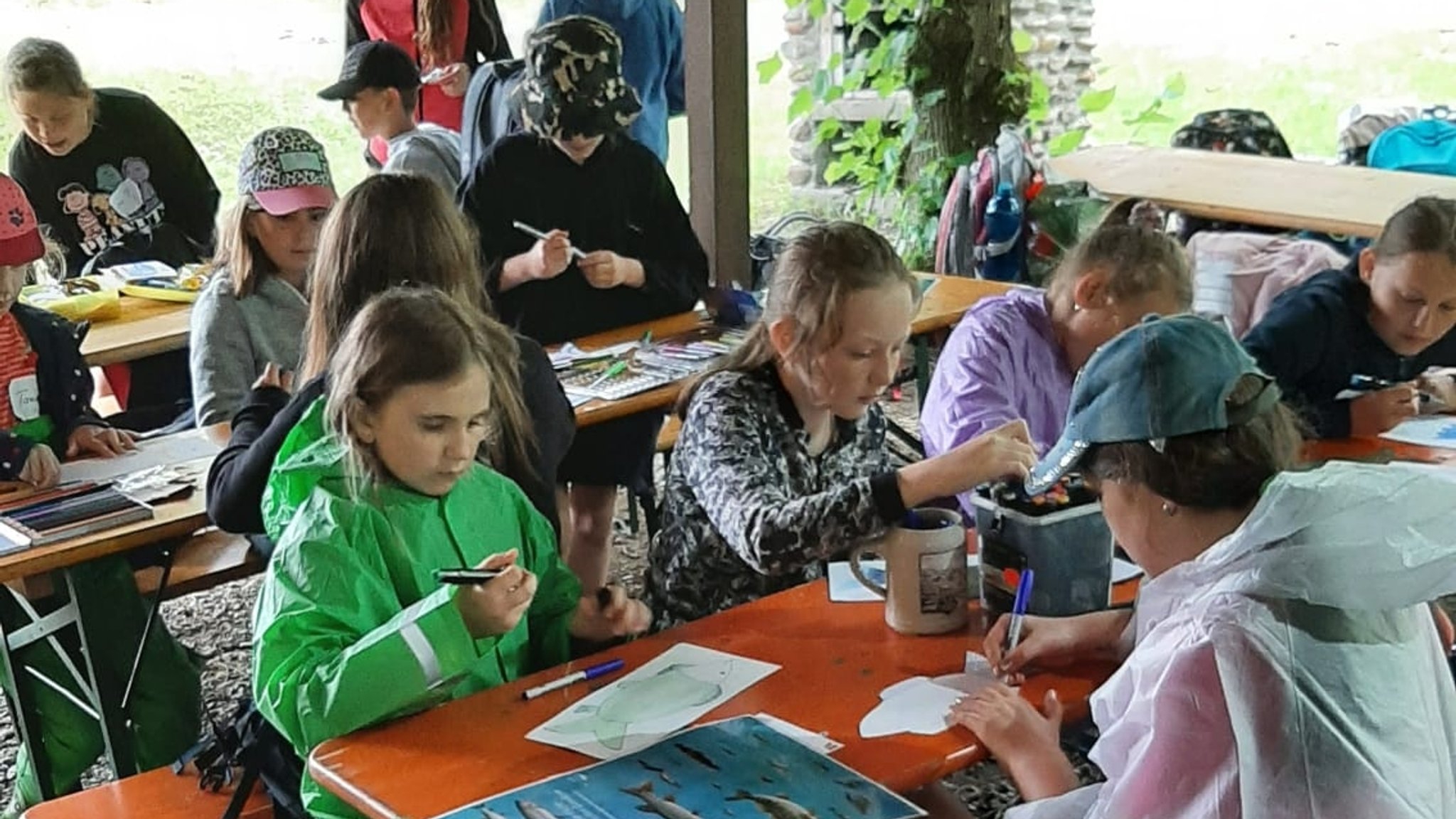 Kinder sitzen auf Bierbänken und malen und basteln.