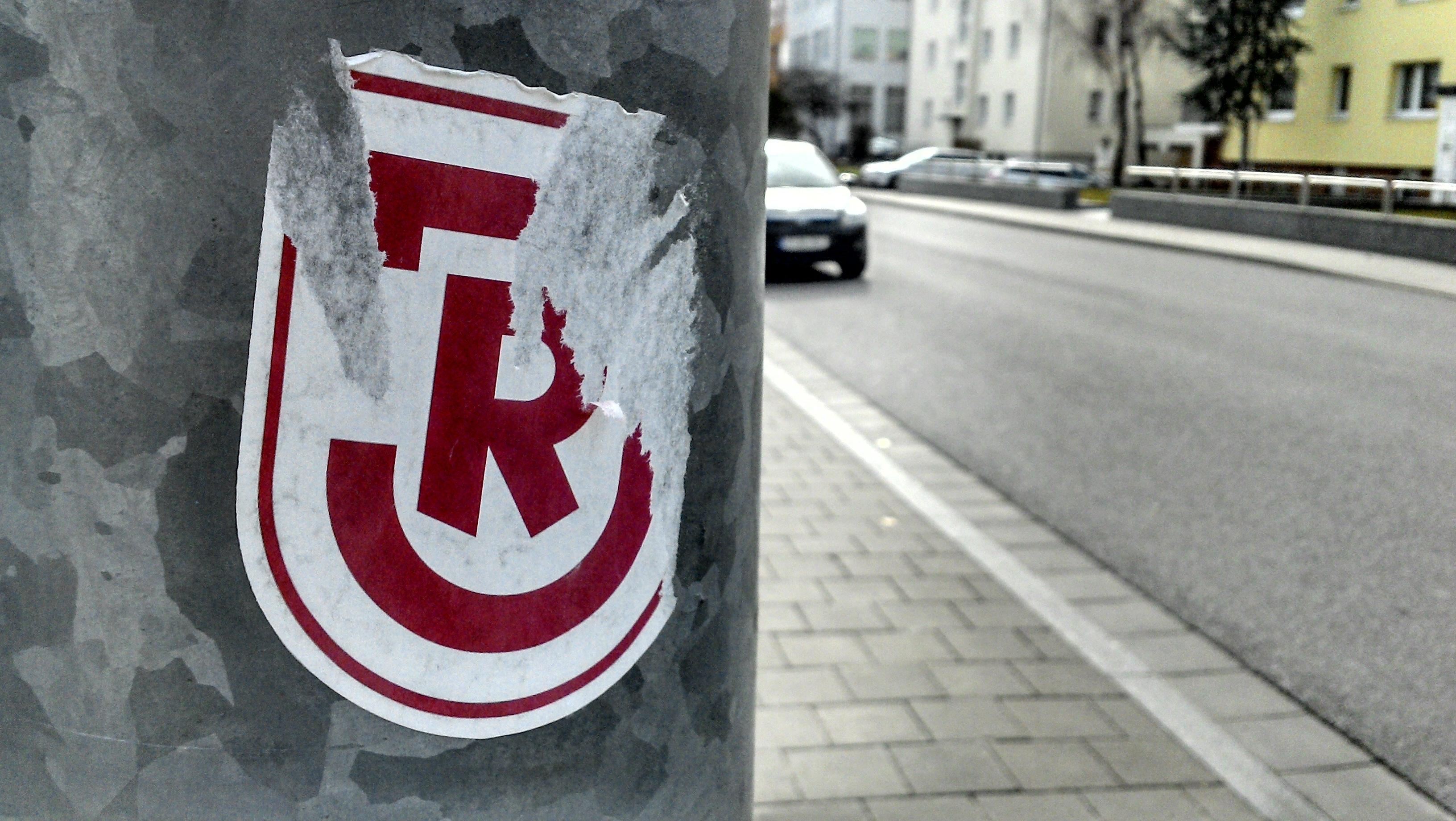 Archivbild: Ein halb abgerissener Aufkleber des SSV Jahn an einer Straßenlaterne
